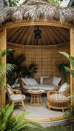 an outdoor living area with wicker furniture and palm leaves on the floor, surrounded by greenery