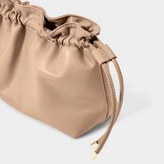 Discover the latest addition to the Katie Loxton family - the Hailey Crossbody Clutch in soft tan! This versatile bag offers you two stylish ways to wear it - either as a trendy crossbody for an effortless day look or as an elegant clutch to elevate any evening outfit. With its drawstring closure detail, vegan leather material, and gleaming gold-tone hardware, this bag exudes understated luxury and attention to detail. Sure to become a staple in your wardrobe, and a piece you can rely on for yea Versatile Taupe Shoulder Bag For Travel, Versatile Neutral Bag With Adjustable Strap, Versatile Brown Shoulder Bag For Spring, Versatile Taupe Crossbody Bag, Brown Shoulder Bag For Spring On-the-go, Spring Soft Leather Beige Bag, Beige Soft Leather Bag For Spring, Chic Neutral Shoulder Bag For On-the-go, Chic Solid Color Pouch Bag