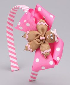 a pink and white polka dot headband with a brown teddy bear on the top