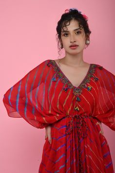 Red kaftan tunic with all-over multicolored Leheriya print, embroidered V-neckline and asymmetric hem. Comes with braided tie-up belt.
Component: 2
Printed, Embroidered
Neckline: V-Neck
Sleeve Length: Three Quarter
Fabric: Georgette
Color: Red
Asymmetric hem
Braided belt with tassels
Note: The inner slip and headscarf worn by the model is not for sale - Aza Fashions Kaftan For Women, Kaftan Tunic, Braided Belt, Embroidered Neckline, Kaftan Dress, Aza Fashion, Head Scarf, Asymmetric Hem, Three Quarter