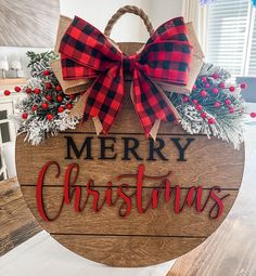 a wooden sign that says merry christmas with red and black plaid bows on it's front