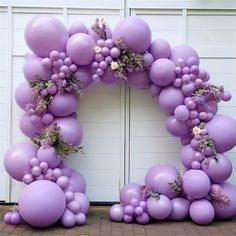 a purple balloon arch with flowers and greenery