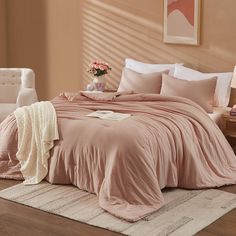 a bed with pink comforters and pillows in a living room next to a chair