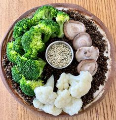 broccoli, cauliflower, and mushrooms are arranged in a bowl on a table