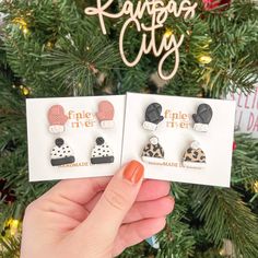 two pairs of earrings are shown in front of a christmas tree with the words pine river written on it