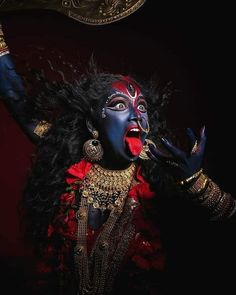 a woman dressed in blue and red with her hands up to the side, holding an object above her head