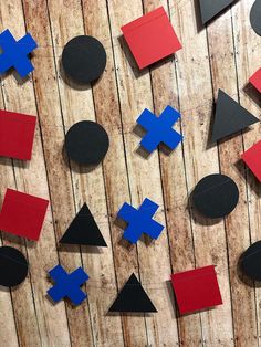 several pieces of paper cut out to look like geometric shapes on a wooden background with black and red circles