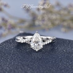 a close up view of a diamond ring on a blue surface with flowers in the background