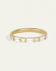 a yellow gold band with three baguettes on the side and two small white stones