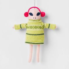 a stuffed animal wearing a green sweater and red headphones hanging from a hook on a wall