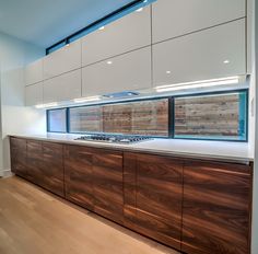 an empty kitchen with wooden cabinets and white counter tops, along with wood flooring