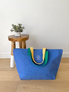 a blue tote bag sitting on top of a wooden floor next to a small table