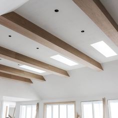 a living room filled with lots of furniture and windows covered in wooden beams on the ceiling