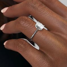 a woman's hand with a diamond ring on her left hand and the other hand holding an engagement ring