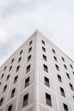 a tall white building with lots of windows on it's side and a sky background