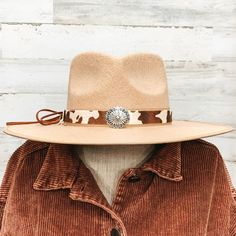 Brown cow print hat band with a single silver stone cluster. It also has leather like material strands that tie it together. It is laying on a piece of wood that is pictured of a white background. Adjustable Silver Hat Bands For Festivals, Adjustable Silver Hat Band For Rodeo, Silver Western Hat Band For Rodeo, Silver Adjustable Hat For Rodeo, Western Adjustable Silver Hat Band, Western Style Silver Adjustable Hat Band, Adjustable Silver Fedora Hat, Cow Print Hat, Western Hats For Women