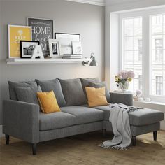 a living room with a gray couch and yellow pillows on the floor next to a window