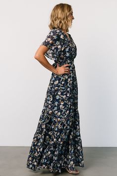 Baltic Born exclusive style Dark blue floral design with hints of orange, green, light blue, and beige Lightweight, flowing chiffon material Surplice neckline Flutter sleeves Keyhole at back neck Waist detail with attached ties at sides Angled tiered maxi skirt Midi length lining 100% Polyester Trina is 5'6, cup size 32D, size 2 and is wearing size S Baltic Born Floral Dress, Blue Floor-length Floral Print Dress, Black A-line Maxi Dress With Floral Print, Bohemian Blue V-neck Floral Dress, Black Floral Print Maxi Dress With V-neck, Tiered Maxi Skirt, Chiffon Material, Flutter Sleeve, Midi Length