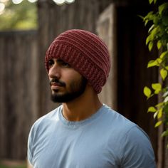 a man with a beard wearing a red knitted hat in front of a wooden fence