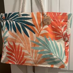 an orange, blue and green tropical print bag hanging on a white door with rope