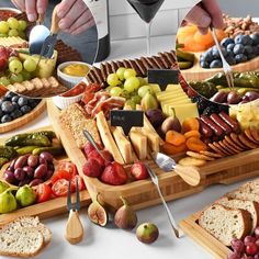 a table topped with lots of different types of cheeses and fruit on top of wooden trays