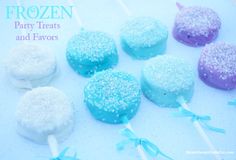 frozen party treats and favors on a white plate with blue ribbon around the lollipops