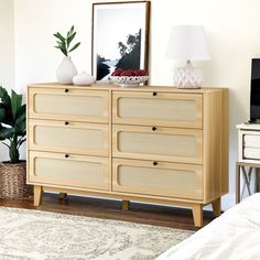 a bedroom with a dresser, lamp and pictures on the wall