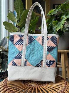 a blue and pink bag sitting on top of a wicker table next to a potted plant