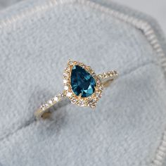 an engagement ring with a pear shaped blue stone surrounded by small white and yellow diamonds