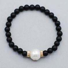 A touch of classic freshwater pearl adds the perfect contrast to the matte black onyx. Made with 6mm back onyx gemstones and a large freshwater pearl in the center. Easy wear and effortless bracelet stacking with stretch cord design. Bracelet made to fit average 6.75 inch wrist size. Please contact us if you have any sizing questions or would like a custom size. Adjustable Black Pearl Beaded Bracelets, Classic Black Jewelry With Pearl Charm, Black Minimalist Jewelry With Pearl Charm, Black Pearl Beaded Bracelets, Minimalist Black Jewelry With Pearl Charm, Black Pearl Bracelets With Round Beads, Adjustable Black Pearl Jewelry, Elegant Black Pearl Bracelet With Round Beads, Black Pearl Bracelets As Gift