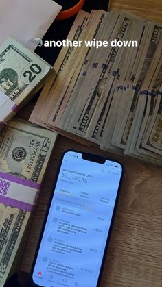 a phone sitting on top of a wooden table next to stacks of money and notes