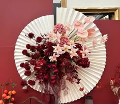 a bouquet of flowers in a vase sitting on a table next to a red wall