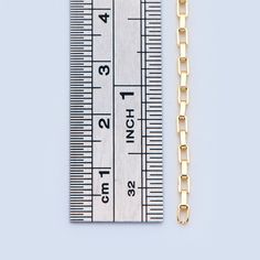 a ruler with a chain attached to it next to a piece of gold jewelry on a white background