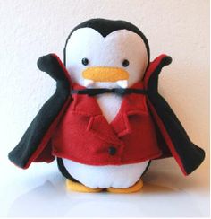 a stuffed penguin with a red jacket and black pants on it's head, standing in front of a white wall