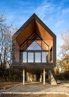 a large wooden structure sitting on top of a dirt field with stairs leading up to it