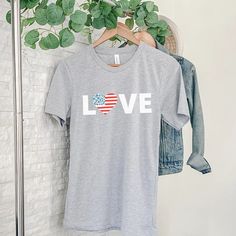 a t - shirt that says love with an american flag in the center on a hanger