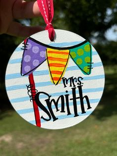 a hand holding a personalized ornament for a child's birthday party