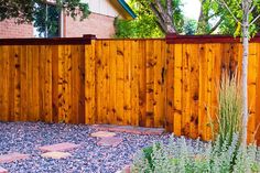 a wooden fence in front of a house with gravel on the ground next to it