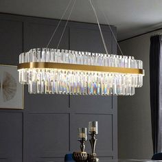 a chandelier hanging over a dining table in a room with gray walls and blue chairs