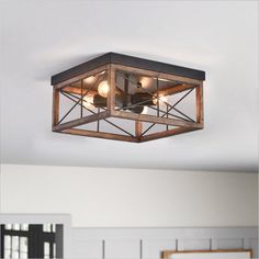 a square light fixture hanging from the ceiling in a room with white walls and windows