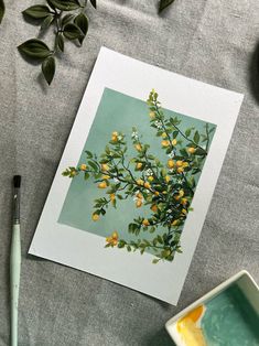 an image of some yellow flowers on a green and white table cloth next to a paintbrush