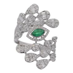 This 14K White Gold Emerald and Diamond Ring featuring a vibrant 0.11 carat Marquise cut Emerald, complemented by 1.24 carats of Round and Baguette cut Diamonds. The gemstones are set in 14 Karat white gold. The ring weighs 5 grams and is sized at 6.5. The rings evil eye and snowstorm motif is presented with a bypass shank and stands at 1.1 inches.  Details:  Item Type: Ring Metal: 14K White Gold Weight: 5 Grams  Size: 6.5 Shank: Bypass Height: 1.1 inches  Stone Details: Gemstone: Emerald Carat: 0.11 Color: Emerald  Cut: Marquise  Side Stone Details: Gemstone: Diamond Cut: Round and Baguette Color: White Carat: 1.24 CTW Luxury Marquise Emerald Ring With Diamonds, Emerald Cut Multi-stone Diamond Ring, Luxury Multi-stone Emerald Ring With Diamonds, Marquise Diamond Multi-stone Jewelry, Multi-stone Diamond Baguette Cut Jewelry, Emerald Ring With Baguette Diamonds In Fine Jewelry Style, Emerald Ring With Baguette Diamonds Fine Jewelry, Fine Jewelry Multi-stone Emerald Diamond Ring, Exquisite Multi-stone Emerald Diamond Ring