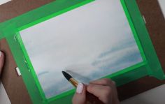 someone is drawing something on a piece of paper with a pencil and watercolors