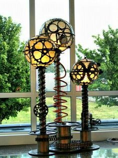 three lamps sitting on top of a glass table next to a window with trees in the background