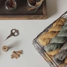 yarn, scissors and other crafting supplies are sitting on a table next to a basket