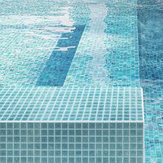 an empty swimming pool with blue tiles on the floor and water reflecting off it's surface