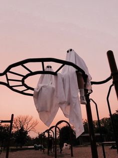 there are two cloths hanging from the top of a metal structure with trees in the background