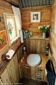 a small bathroom with wooden walls and wood flooring, along with a toilet in the corner