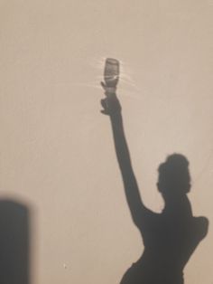 a shadow of a person holding a tennis racket in the air with their hand