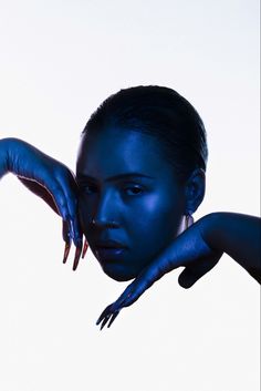 a woman with blue paint on her face and hands, posing for the camera in front of a white background